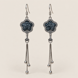 Midnight Blossom floral tassel earrings, front view showing deep indigo batik with pale flowing curves in flower-shaped metal frames with three chain tassels with rounded drops.