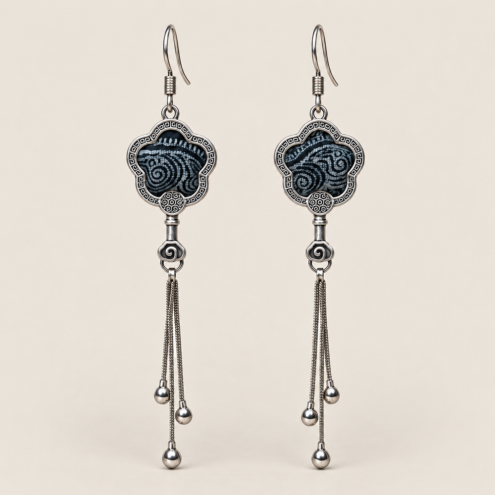 Midnight Blossom floral tassel earrings, front view showing deep indigo batik with pale flowing curves in flower-shaped metal frames with three chain tassels with rounded drops.