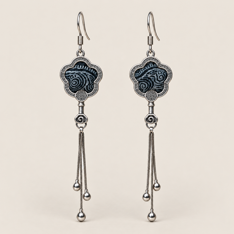Midnight Blossom floral tassel earrings, front view showing deep indigo batik with pale flowing curves in flower-shaped metal frames with three chain tassels with rounded drops.