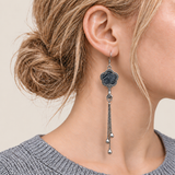 Close-up of Midnight Blossom floral tassel earrings worn with deep indigo batik with pale flowing curves facing outward.