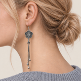 Close-up of Midnight Blossom floral tassel earrings worn with the bird-and-branch metal relief reverse facing outward.