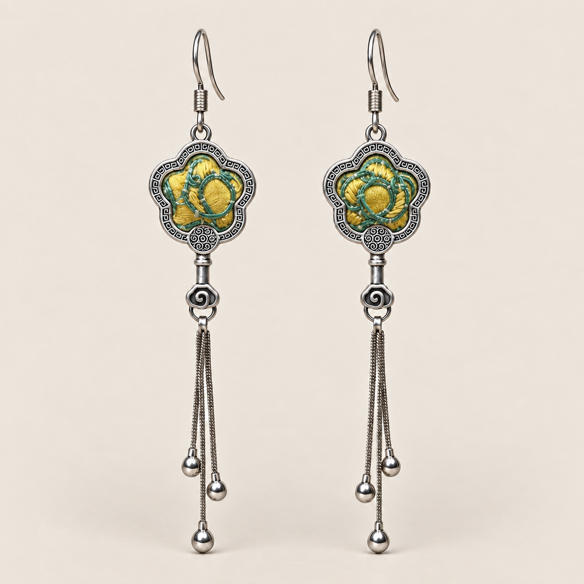 Golden Meadow floral tassel earrings, front view showing yellow and green floral embroidery in flower-shaped metal frames with three chain tassels with rounded drops.