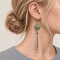 Close-up of Golden Meadow floral tassel earrings worn with yellow and green floral embroidery facing outward.
