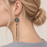 Close-up of Golden Meadow floral tassel earrings worn with the bird-and-branch metal relief reverse facing outward.
