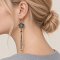 Close-up of Golden Meadow floral tassel earrings worn with the bird-and-branch metal relief reverse facing outward.