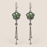 Jade Whisper floral tassel earrings, front view showing soft green floral embroidery in flower-shaped metal frames with three chain tassels with rounded drops.