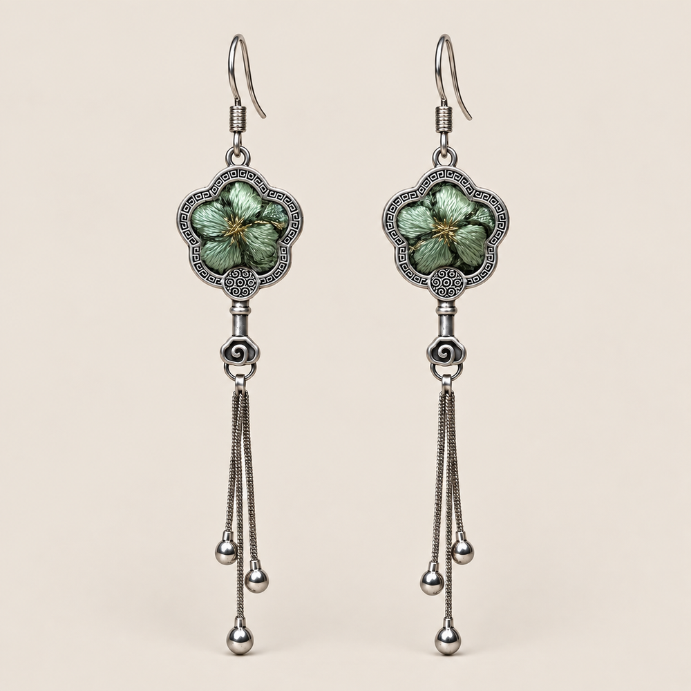 Jade Whisper floral tassel earrings, front view showing soft green floral embroidery in flower-shaped metal frames with three chain tassels with rounded drops.