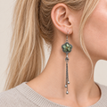 Close-up of Jade Whisper floral tassel earrings worn with soft green floral embroidery facing outward.