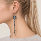 Close-up of Jade Whisper floral tassel earrings worn with the bird-and-branch metal relief reverse facing outward.