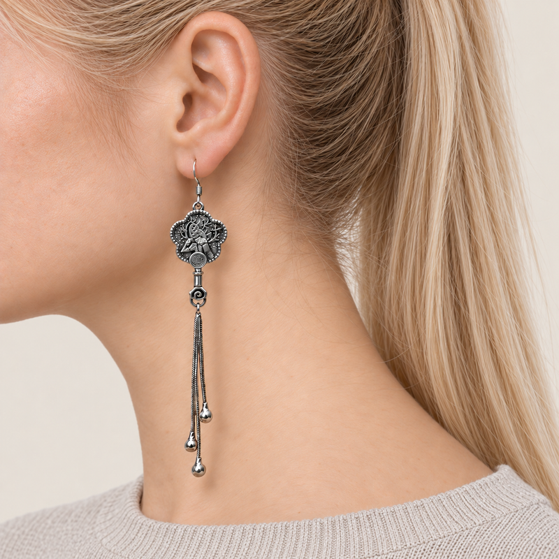 Close-up of Jade Whisper floral tassel earrings worn with the bird-and-branch metal relief reverse facing outward.