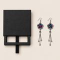 Black drawer-style box pictured beside Rose Constellation floral tassel earrings, with textile fronts and metal relief backs visible.