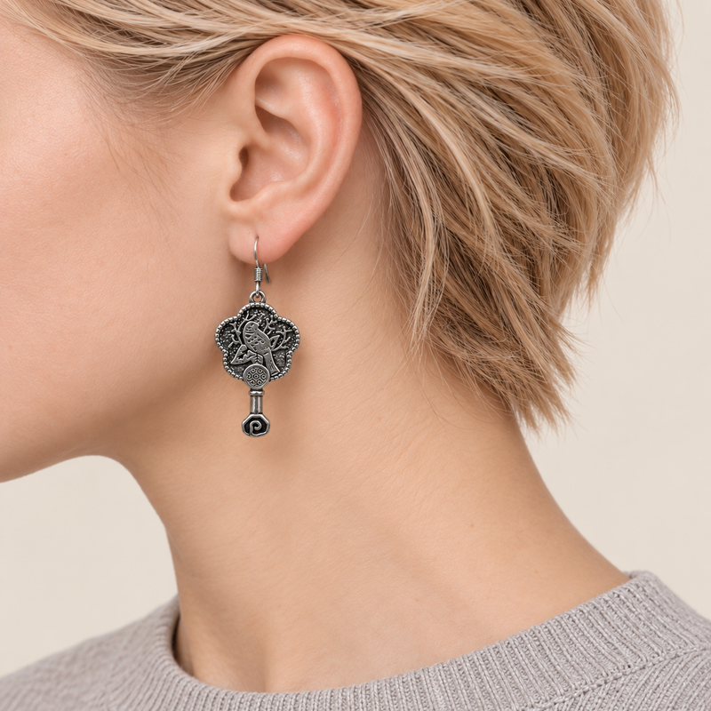 Close-up of Fuchsia Dawn floral earrings worn with the bird-and-branch metal relief reverse facing outward.
