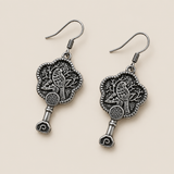 Fuchsia Dawn floral earrings laid diagonally with bird-and-branch relief backs facing up and small spiral drops visible.