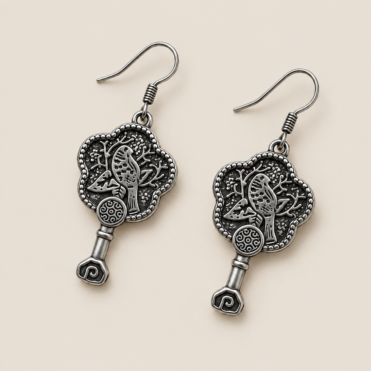 Fuchsia Dawn floral earrings laid diagonally with bird-and-branch relief backs facing up and small spiral drops visible.