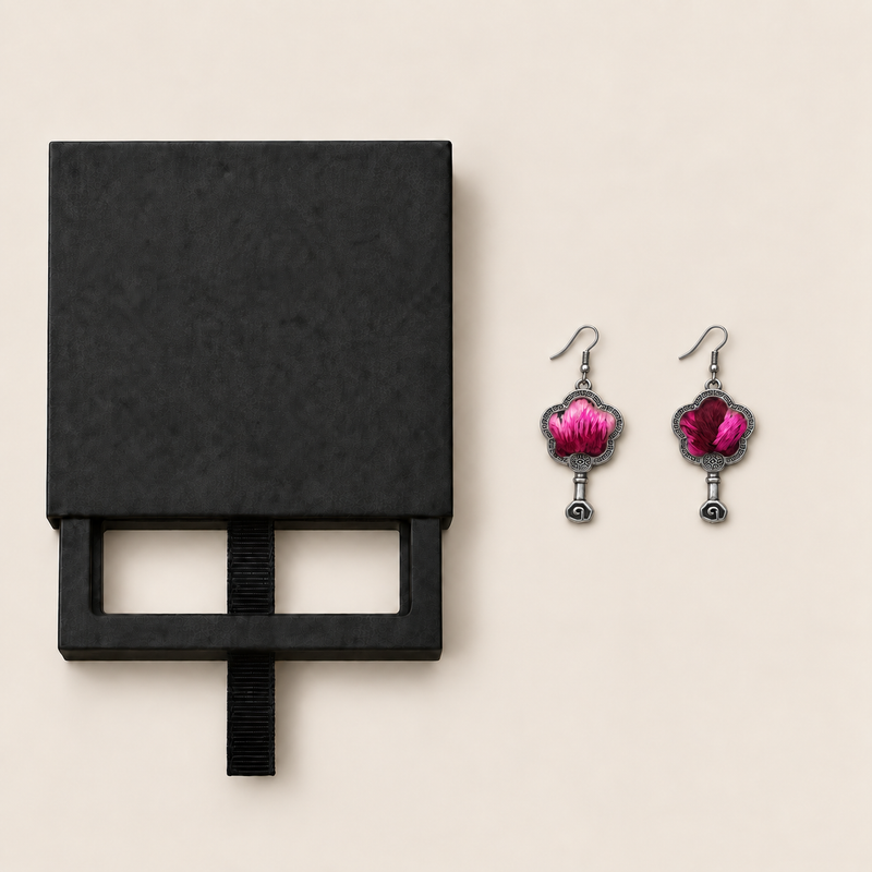 Black drawer-style box pictured beside Fuchsia Dawn floral earrings, with textile fronts and metal relief backs visible.