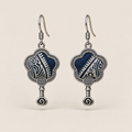 Indigo Echo floral earrings, front view showing pale geometric lines on deep indigo batik in flower-shaped metal frames with small spiral drops.