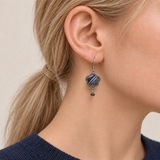 Close-up of Indigo Echo floral earrings worn with pale geometric lines on deep indigo batik facing outward.