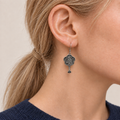 Close-up of Indigo Echo floral earrings worn with the bird-and-branch metal relief reverse facing outward.