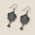 Indigo Echo floral earrings laid diagonally with bird-and-branch relief backs facing up and small spiral drops visible.