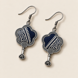 Indigo Echo floral earrings laid diagonally with pale geometric lines on deep indigo batik facing up and small spiral drops visible.