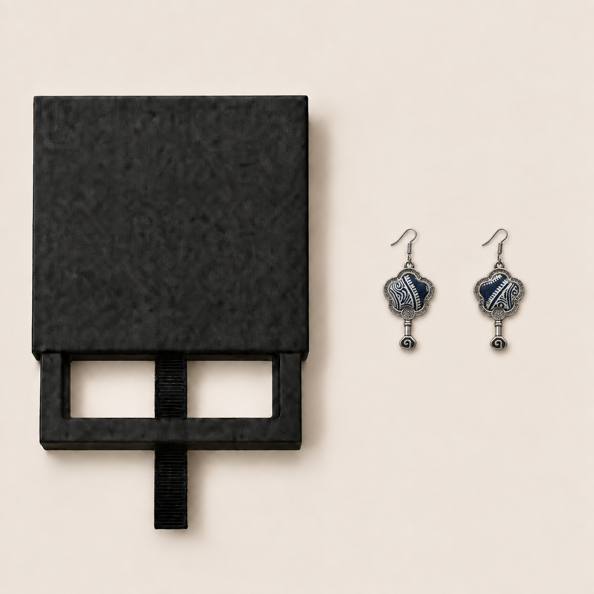 Black drawer-style box pictured beside Indigo Echo floral earrings, with textile fronts and metal relief backs visible.