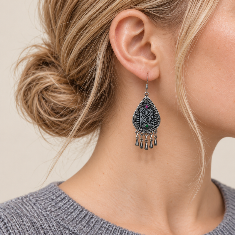 Close-up of a worn Midnight Currents earring showing pale batik spirals, pink and green accents and five short drops.