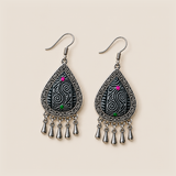 Midnight Currents earrings lying face up, showing differing pale spiral patterns on dark batik textile with pink and green accents.