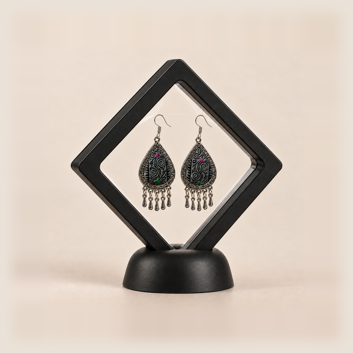 Midnight Currents earrings displayed inside a clear diamond-shaped frame with a black border and base.