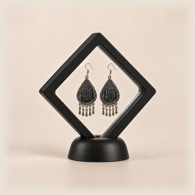 Midnight Currents earrings displayed inside a clear diamond-shaped frame with a black border and base.