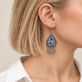 Close-up of a Silver Tide earring worn with its blue and silver-toned embroidered front facing outward.