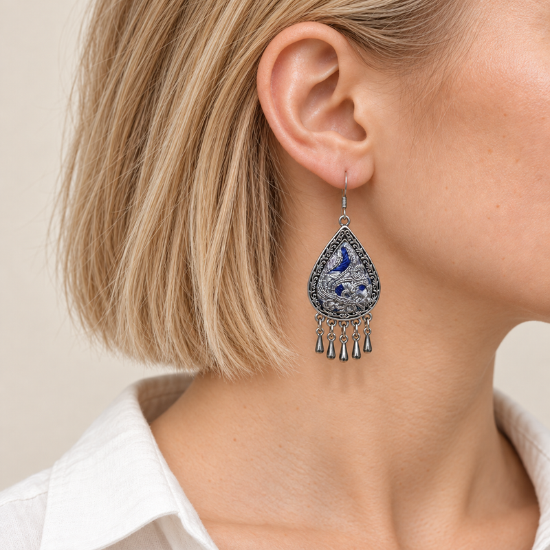 Close-up of a Silver Tide earring worn with its blue and silver-toned embroidered front facing outward.