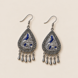 Angled front view of Silver Tide earrings showing silver-toned embroidery curves over deep blue.