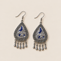 Angled front view of Silver Tide earrings showing silver-toned embroidery curves over deep blue.