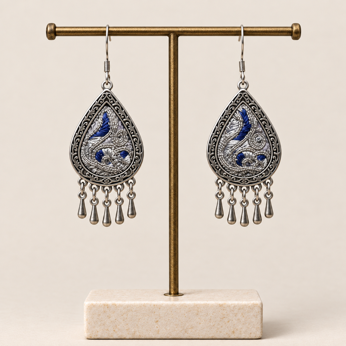 Silver Tide earrings hanging from a display stand with their embroidered fronts facing forward.