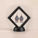 Silver Tide earrings shown inside a black display frame; sales packaging is not confirmed.