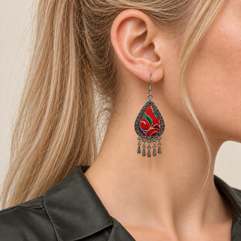 Close-up of a Crimson Aurora earring worn with red embroidery, green and purple accents and pale curved lines facing outward.