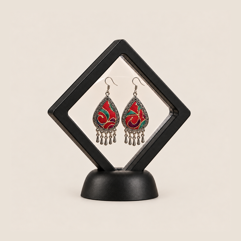 Crimson Aurora earrings displayed inside a transparent, diamond-oriented black frame on a black base.