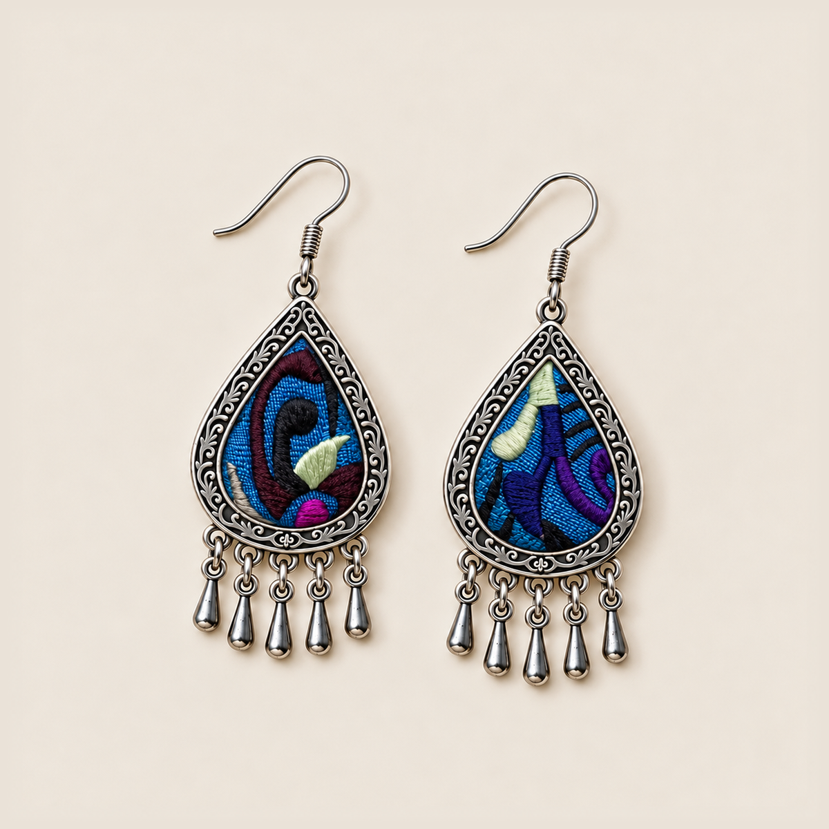 Violet Reverie earrings laid flat, showing different embroidered patterns in blue, purple, black and pale green.