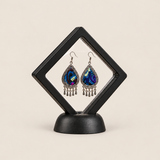 Violet Reverie earrings displayed inside a transparent, diamond-oriented black frame on a black base.