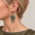 Close-up of a Petal Serenade earring worn with the sculpted wave-relief metal reverse facing outward.