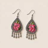 Petal Serenade earrings laid flat, showing different pink floral embroidery patterns with green leaves on a dark ground.