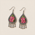 Petal Serenade earrings laid flat, showing different pink floral embroidery patterns with green leaves on a dark ground.