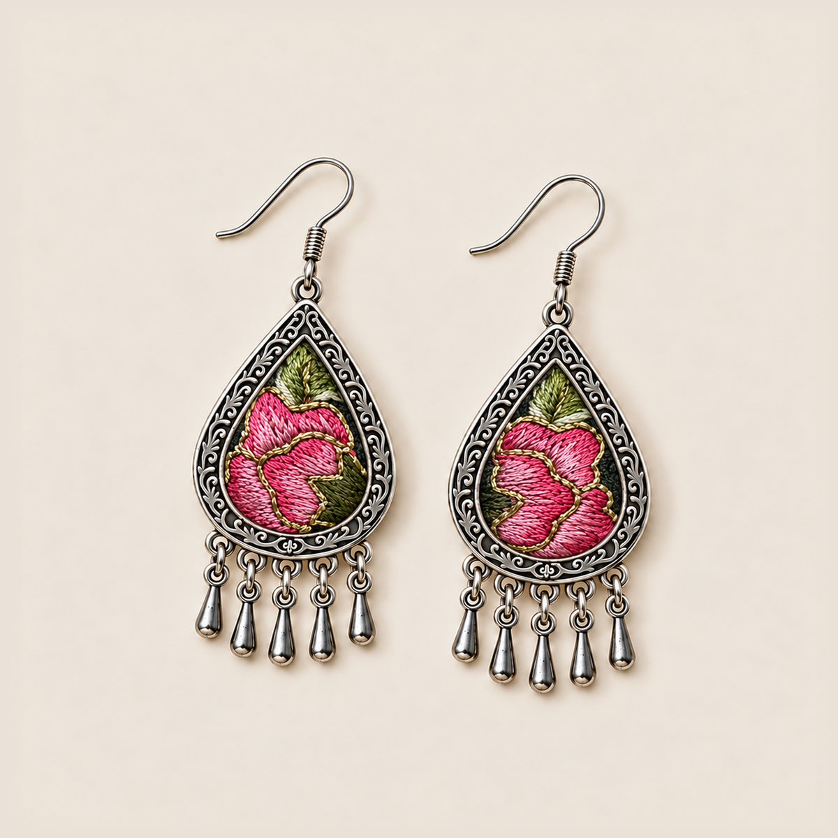 Petal Serenade earrings laid flat, showing different pink floral embroidery patterns with green leaves on a dark ground.
