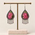 Petal Serenade floral teardrop earrings hanging from a T-bar stand, with pink petals, green leaves and five short drops each.