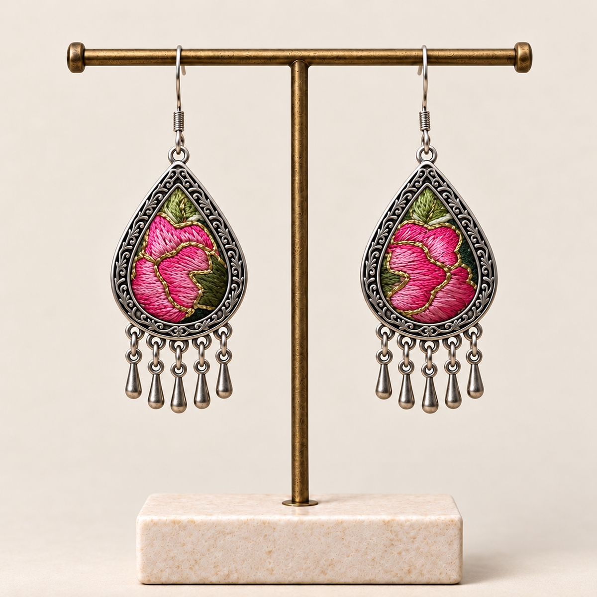 Petal Serenade floral teardrop earrings hanging from a T-bar stand, with pink petals, green leaves and five short drops each.