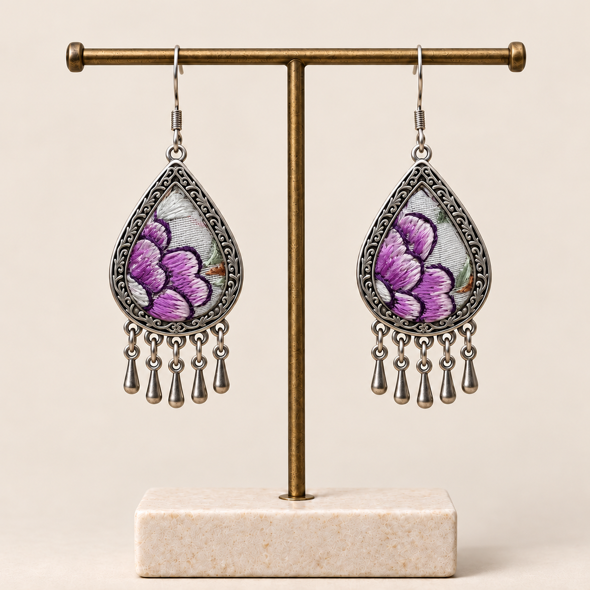 Lavender Sonata floral teardrop earrings hanging from a T-bar stand, with purple embroidered petals and five short drops each.