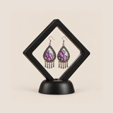 Lavender Sonata earrings displayed inside a transparent, diamond-oriented black frame on a black base.