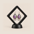Lavender Sonata earrings displayed inside a transparent, diamond-oriented black frame on a black base.