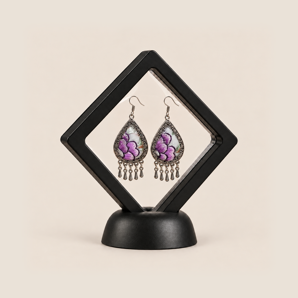 Lavender Sonata earrings displayed inside a transparent, diamond-oriented black frame on a black base.