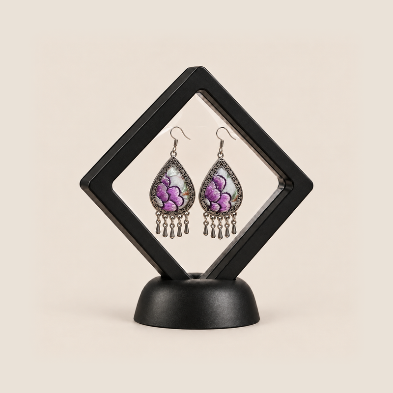 Lavender Sonata earrings displayed inside a transparent, diamond-oriented black frame on a black base.